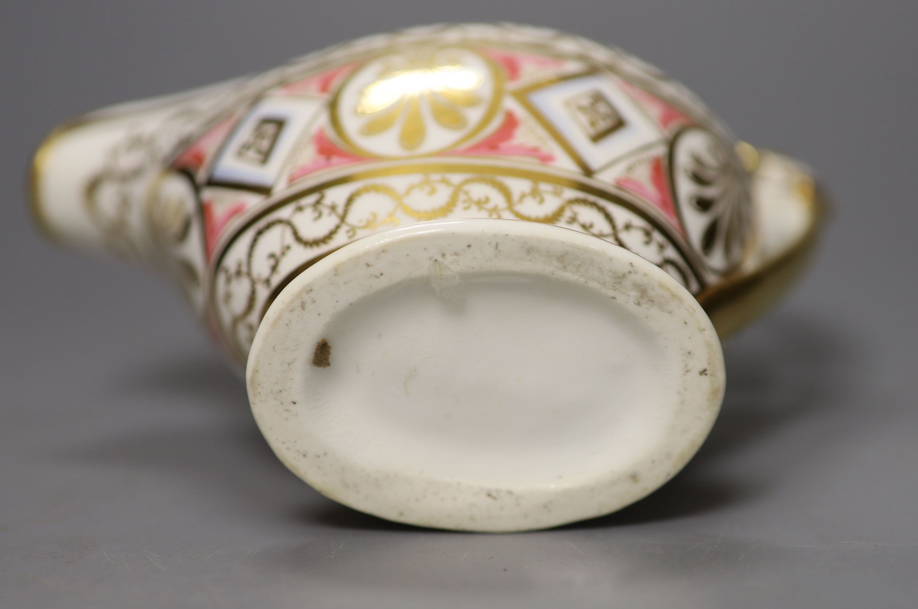 A rare English porcelain sauceboat, with swan neck handle gilded with alternating oval and diamond shaped panels and puce festoons,